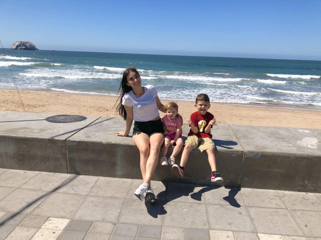 Family relaxing on the Malecón seawall in Mazatlán with the ocean in the background.