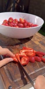 Chopping fresh strawberries on a wooden cutting board for fresas con crema or Mexican Strawberries with Cream Recipe.