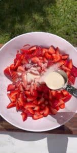 Adding creamy mixture to chopped strawberries for Fresas con Crema dessert.