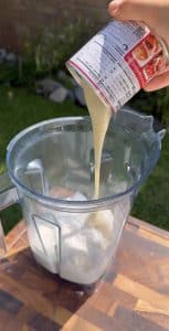 Adding sweetened condensed milk into blender for fresas con crema.