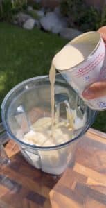 Pouring evaporated milk into blender for fresas con crema.