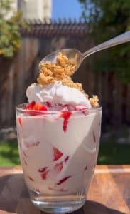 Garnished strawberries and cream dessert with whipped cream and granola.