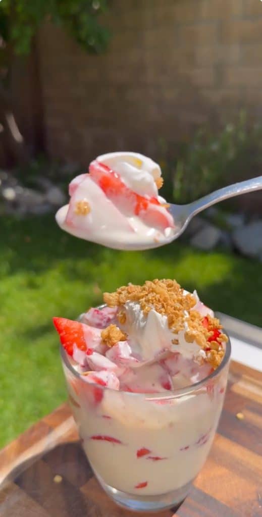 Spoonful of creamy Mexican strawberries and cream dessert topped with granola.
