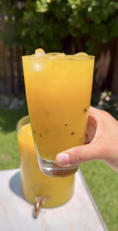 Glass full of icy mango passion fruit agua fresca ready for the Summer.