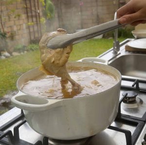 Chicken being removed from steaming pot.