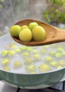 Ladle lifting tender, pale green tomatillos from simmering water.
