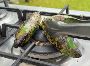 Charred jalapeños roasting directly over a burner.