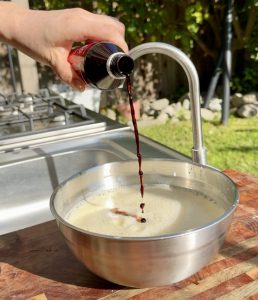 Vanilla extract being poured into the wet mixture for buñuelos.