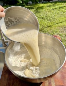 Wet mixture being poured into dry ingredients to make buñuelos batter.
