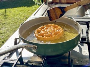 Buñuelo frying in hot oil until lightly golden on the bottom.