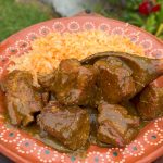 Pork chile verde with tender pork shoulder and spareribs in roasted tomatillo sauce served with Mexican red rice