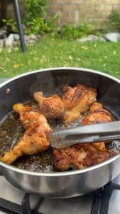 Seasoned chicken pieces browned in a large pot.